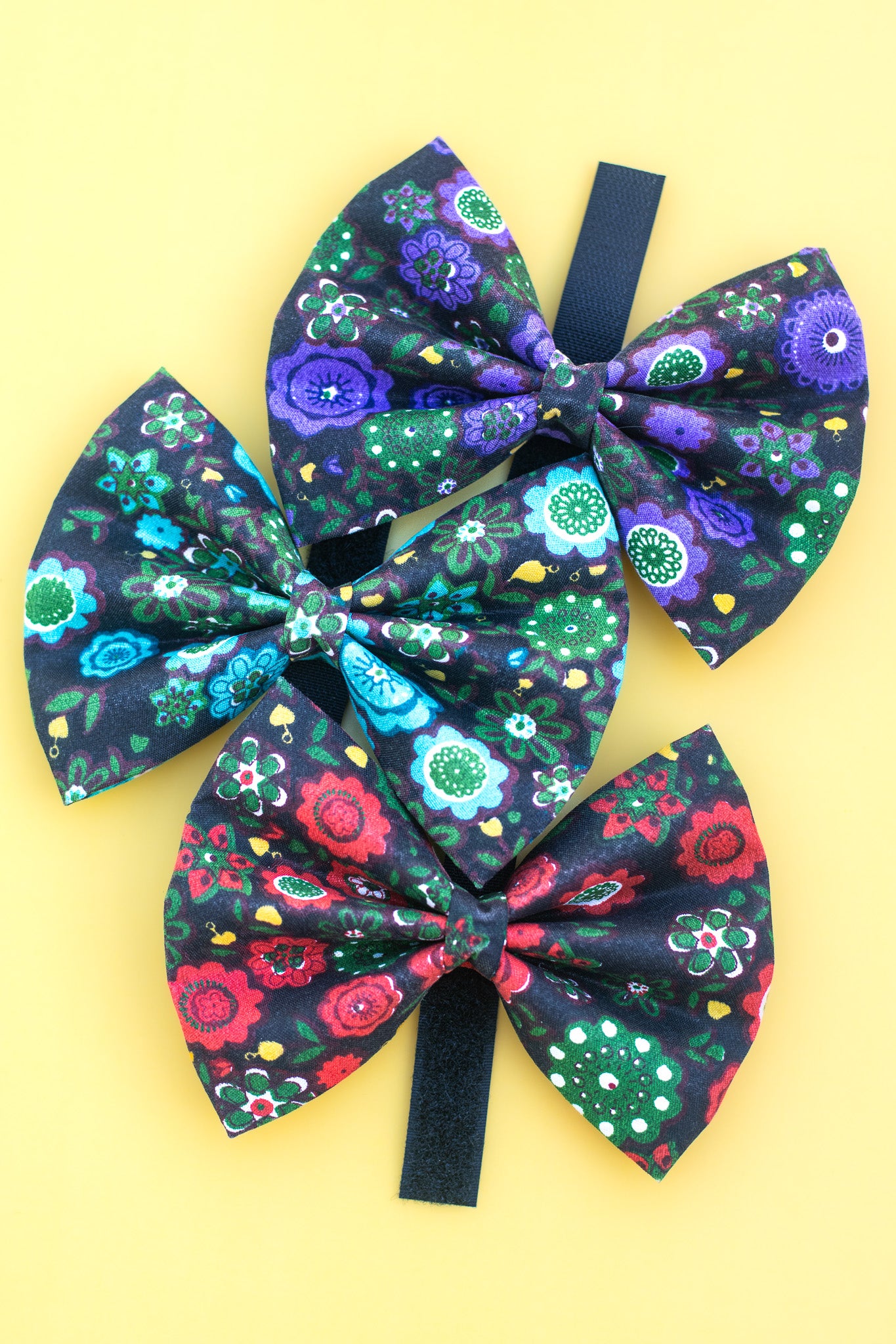 Three floral-patterned hair bows on a yellow background